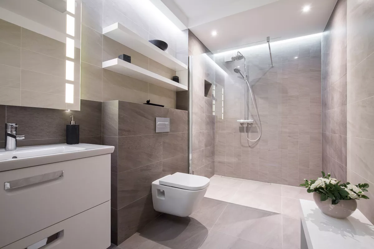 Ein modernes und helles Badezimmer in hellen Grautönen mit großer bodentiefer Dusche
